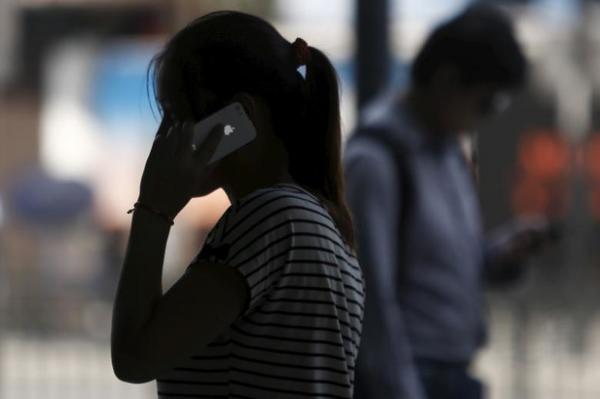 A woman speaks on her iPhone as she walks on a busy street in downtown Shanghai. REUTERS/Aly Song